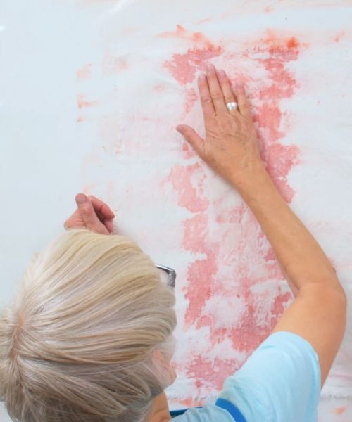 Claire Benn out of this earth Claire benn using her hands to blend light red paint