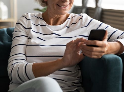 Woman sitting on couch scrolling on mobile phone